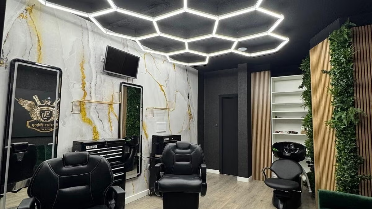 Interior de Antonio Blanco Barbería con sillones negros y techo geométrico iluminado